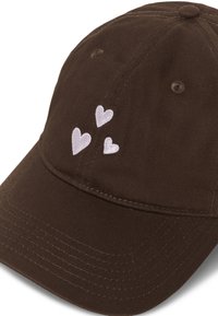 Casquette de baseball marron foncé avec trois petits cœurs blancs brodés sur le panneau avant au-dessus de la visière.