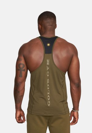 Muscular man wearing olive green Gold's Gym tank top and shorts, showing back with tattoos on left arm against plain background.