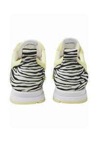 Yellow sneakers with a black and white zebra print heel. Soft material, cushioned design, and white soles. Brand logo visible on the heel.