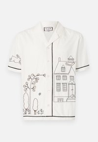 Camisa blanca de manga corta con bordado en contorno negro de una casa, árboles y un conejo. Con botones en la parte frontal y bordes en contraste.