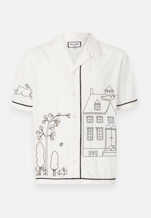 Chemise blanche à manches courtes ornée d'une broderie en contour noir représentant une maison, des arbres et un lapin. Fermeture à boutons sur le devant et bords contrastants.