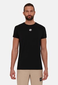 Schwarzes Kurzarm-T-Shirt aus Baumwolle, mit rundem Ausschnitt und einem kleinen weißen runden Logo auf der Brust.