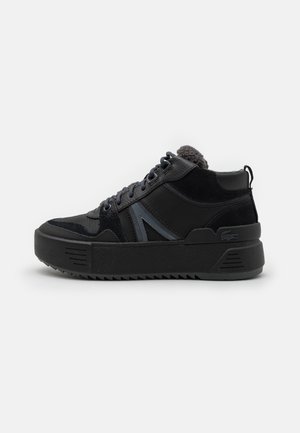 Zwarte hoge sneaker met dikke zool, veters aan de voorkant, getextureerde panelen en een fleece voering zichtbaar bij de enkelkraag.