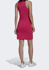 Růžové úzké šaty bez rukávů vyrobené z hladké látky, s designem na zádech a jednoduchými lemy. Spárováno s bílými teniskami s iridescenčními akcenty.