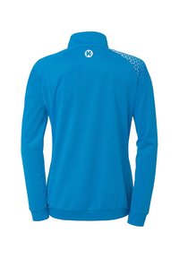Blå atletisk jakke med høj krave, glat tekstur og mesh-detaljer på skulderen. Har logo på den øverste del af ryggen.