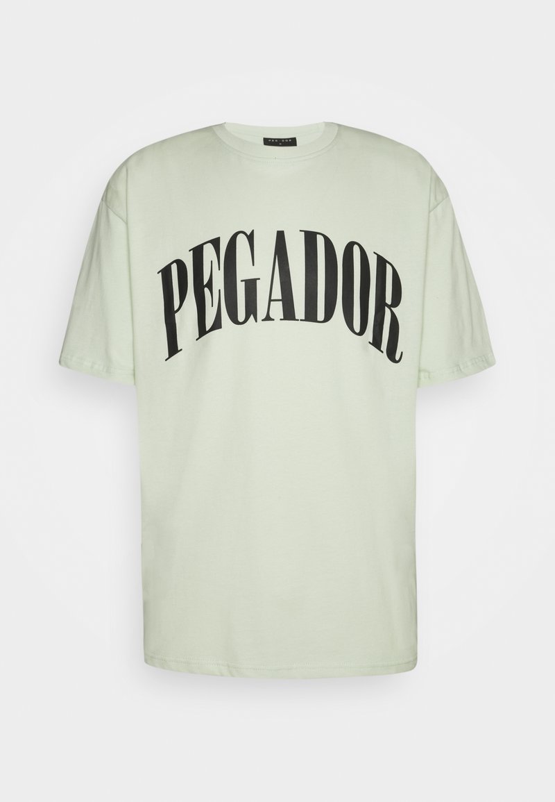 Vaaleanvihreä puuvillainen T-paita, jossa on lyhyet hihat ja pyöreä pääntie. Paidassa on suuret mustat kirjaimet, jotka muodostavat kaarevan "PEGADOR"-tekstin.