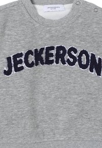 Felpa grigia con collo e polsini a costine. Presenta "JECKERSON" ricamato in terry blu navy sul petto. Materiale in cotone liscio.