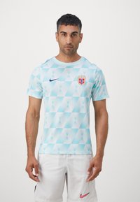 Hele helesinise kolmnurga mustriga spordijerseys, millel on lühikesed varrukad, varustatud Nike logo ja Norra rahvusmeeskonna embleemiga.