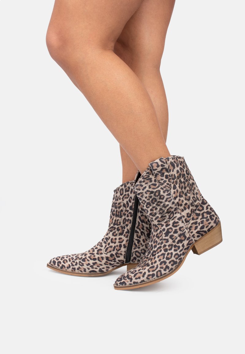 Botas de tobillo con estampado de leopardo, tacón bajo de madera, punta redondeada y cremallera lateral. La tela tiene una textura suave y un patrón animal distintivo.