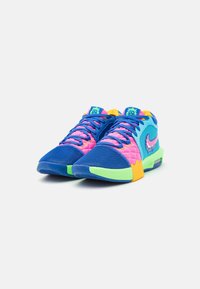 Sneakers Nike con un upper in rete blu, rosa e verde, caratterizzati da un design distintivo, materiali testurizzati e una suola con grip.