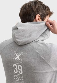 Hoodie gris avec un design graphique au dos mettant en vedette un logo et le numéro "39". Fait de tissu doux, affichant une apparence texturée.