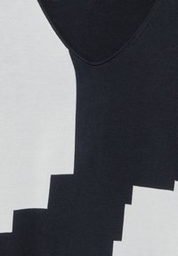Ärmelloses Top mit V-Ausschnitt, das ein geometrisches Schwarz-Weiß-Farbblockmuster aufweist. Hergestellt aus strukturiertem Stoff mit einer glatten Oberfläche.