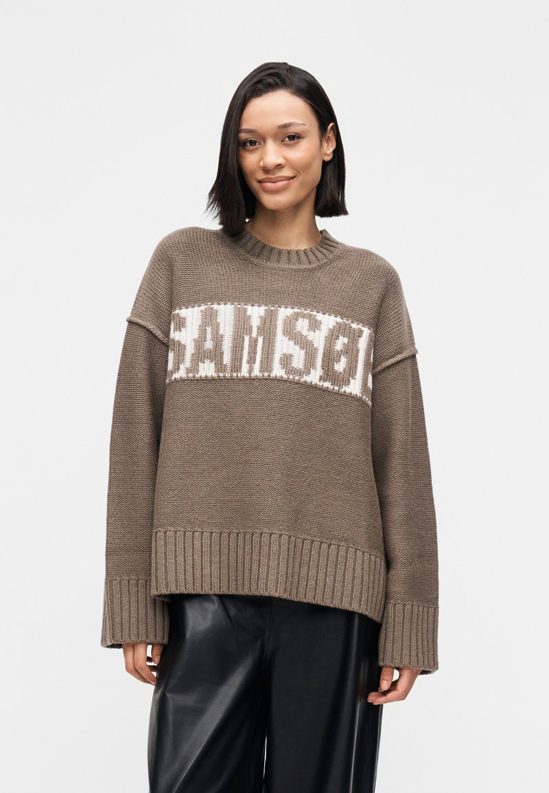 Χοντρό πλεκτό πουλόβερ σε καφέ χρώμα με αντίθετο λευκό μοτίβο "SAMSON" στο στήθος. Διαθέτει φαρδύ ριμπ τελείωμα και μανσέτες.