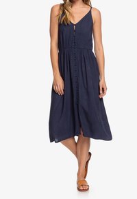 Námořnické midi šaty s předními knoflíky, nastavitelnými ramínky a pasem. Vyrobeny z lehkého materiálu s hladkou texturou.