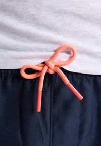 Pantaloni scurți bleumarin cu un elastic la brâu, având un șnur coral legat sub formă de fundiță. Materialul pare ușor, cu o textură netedă.