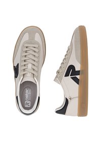 Ljust beige sneakers med en mocka- och slät yta, med svarta accenter och en gummisula, som visar en klassisk design med snören.