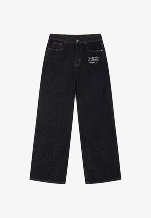 Zwarte jeans met wijde pijpen, vijf zakken, knoopsluiting en een klein wit logo met de tekst "Don Ed Hardy designs" op het rechterdijbeen.