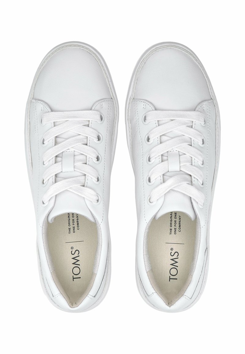 Weiße Schnürschuhe mit niedrigem Schnitt und abgerundeten Zehen sowie gepolsterten Kragen, aus der Vogelperspektive betrachtet, mit TOMS-Branding im Inneren der Schuhe.