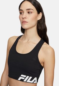 Czarny sportowy top krótki wykonany z elastycznej tkaniny. Posiada okrągły dekolt, szerokie ramiączka oraz wyraźne białe logo FILA z przodu.