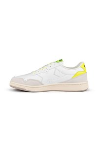 Zapatilla deportiva blanca con acentos de ante gris, tirador en el talón de un amarillo brillante y cordones amarillos a juego. Presenta detalles perforados y suela de goma.
