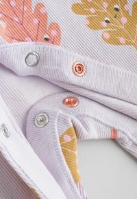 Ljust lila tyg med ribbad textur och färgglada lövmönster. Tryckknappar i silver och roséguld. Mjukt och elastiskt material.