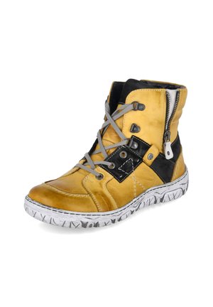 Zapatilla deportiva de piel amarilla de caña alta con detalles en negro, cordones grises, cremallera lateral y suela blanca con marcas negras.