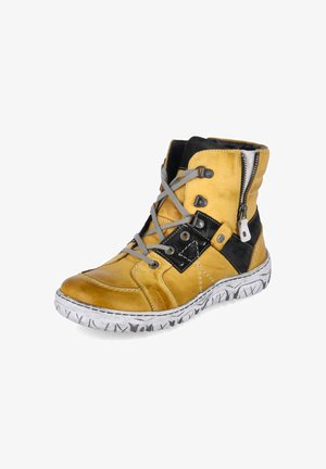 Zapatilla deportiva de piel amarilla de caña alta con detalles en negro, cordones grises, cremallera lateral y suela blanca con marcas negras.