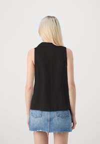 Haut sans manches noir avec un col, texture lisse, assorti à une mini-jupe en denim bleu clair avec des ourlets effilochés et des poches arrière.