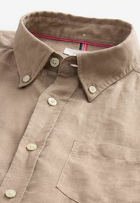 Bruine linnen shirt met een button-down kraag, voorzien van witte knopen, een borstzak en een kleurrijke gestreepte binnenbekleding.