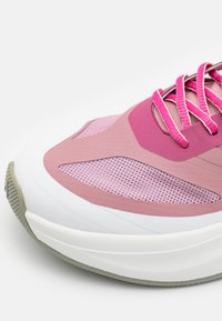 Scarpa da ginnastica leggera con una combinazione di mesh rosa e materiali in gomma, con lacci rosa prominenti e una suola intermedia bianca.