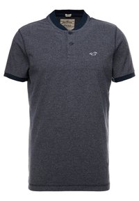 Kortärmad, grå polotröja med en strukturerad yta, marinblå krage och ärmslut, med två knappar vid halsen och en logotypdetalj.