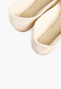 Canvas instap schoenen in roomkleur met textuur geweven interieur, platte zolen en subtiele stiksel rondom de randen. Lichtgewicht en eenvoudig ontwerp.