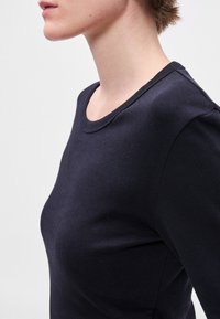 Μαύρο βαμβακερό πουκάμισο μακρυμάνικο με στρογγυλή λαιμόκοψη και ραβδωτή υφή, εφαρμοστό κόψιμο, με ομαλή επιφάνεια και ελάχιστες ραφές.