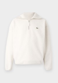 White fleece pullover with a half-zip collar, soft texture, ribbed collar, and a small green logo on the left chest area.