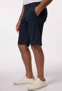 Námořnické modré šortky s knoflíkovým zapínáním a elastickým pasem, se bočními kapsami. V kombinaci s bílými teniskami se šedými akcenty.