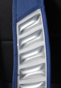 Sangle d'épaule en tissu bleu avec une section en plastique transparent présentant des rainures verticales ; fond noir texturé.