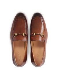 Mocasines de cuero marrón con un acabado suave, puntera redonda y detalle de bitón en tono dorado. El interior es color marrón claro con el logo de la marca grabado.