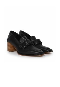 Mocasines de cuero negro con un lazo amplio, puntera afilada y un tacón de madera apilada. Textura suave con un acabado pulido.