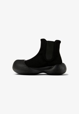 Stivaletto nero realizzato in tessuto con suola in gomma ampia e testurizzata. Presenta pannelli laterali elastici per una facile vestibilità. Design moderno e unico.