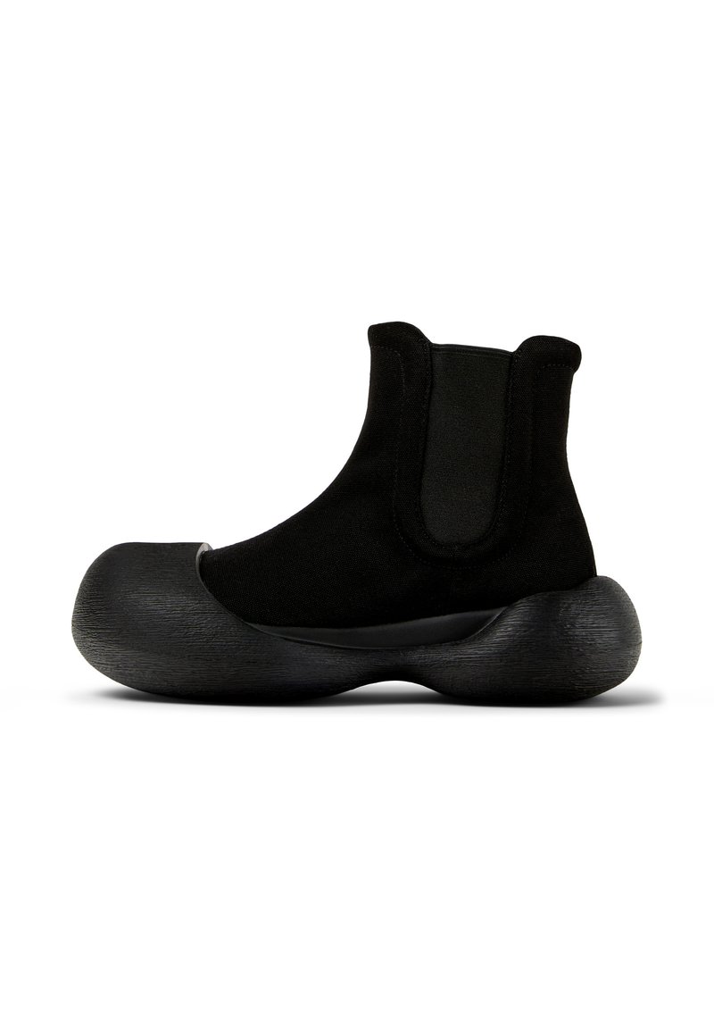 Stivaletto nero realizzato in tessuto con suola in gomma ampia e testurizzata. Presenta pannelli laterali elastici per una facile vestibilità. Design moderno e unico.