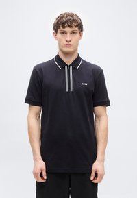 Μαύρο πόλο πουκάμισο με φερμουάρ στη λαιμόκοψη, με λευκές ρίγες στον γιακά και μικρό λευκό λογότυπο "BOSS" στο στήθος. Κοντά μανίκια, βαμβακερό υλικό.