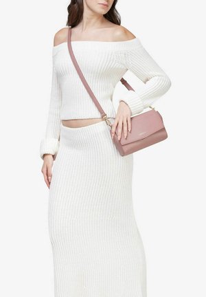 Hvid, ribbet strikket sweater med off-shoulder og matchende nederdel, parret med en lille lyserød crossbody taske med låg og guld hardware.