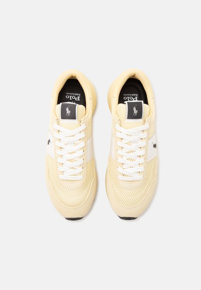Paire de baskets Polo Ralph Lauren jaune pâle avec lacets blancs et détails en mesh, vues de dessus sur fond blanc.