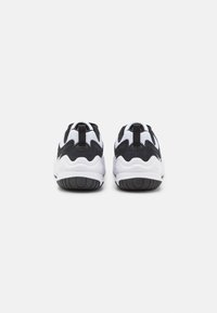 Scarpe da corsa in bianco e nero con tomaia in tessuto lavorato a maglia, design curvo e suola spessa bianca con battistrada in gomma nera.