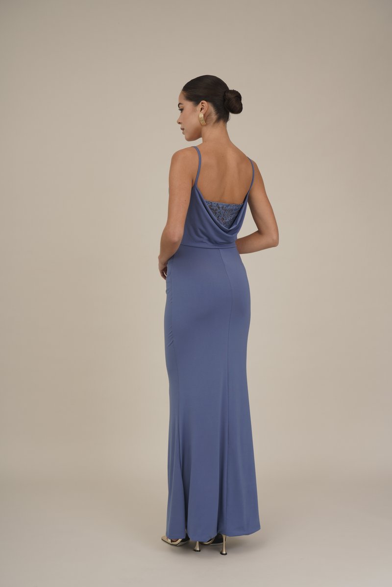Langes, eng anliegendes blaues Kleid mit drapiertem Rücken und Spitze. Es hat dünne Träger und eine glatte Stoffstruktur, kombiniert mit metallischen Absätzen.