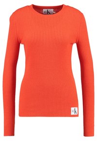 Ribbad orange stickad tröja med långa ärmar och rundad halsringning. Har en liten märkesetikett på nedre vänstra sidan.