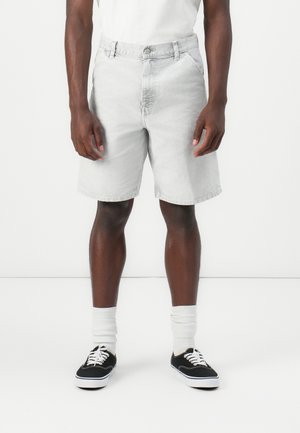 Light gray denim shorts with a straight cut, five pockets, and a button closure. Worn with white crew socks and black sneakers.