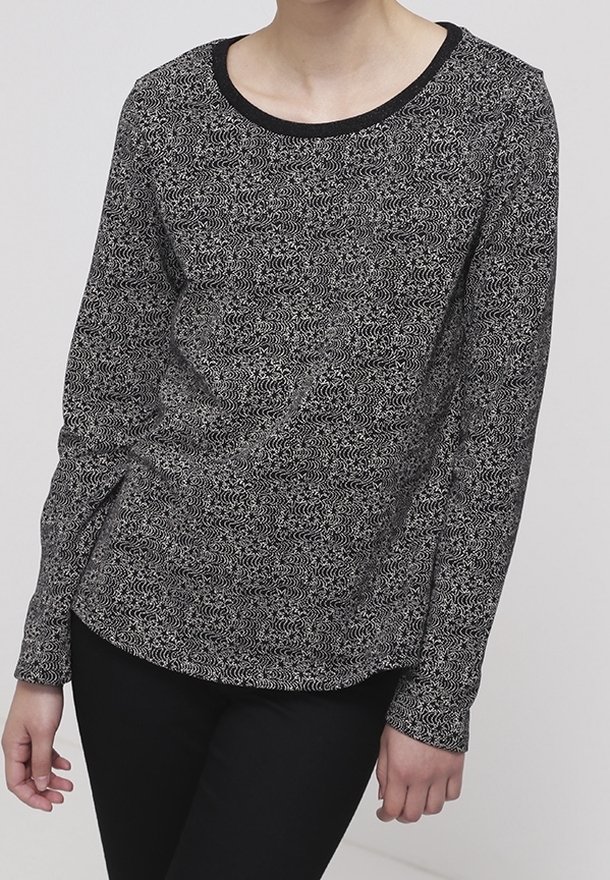 Top de manga larga en blanco y negro con un patrón, escote redondo y tejido texturizado, combinado con pantalones negros.