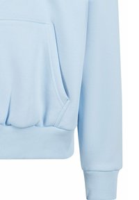 Manche de sweat bleu clair et poche avant avec détails en bord-côte au niveau des poignets et de la taille.