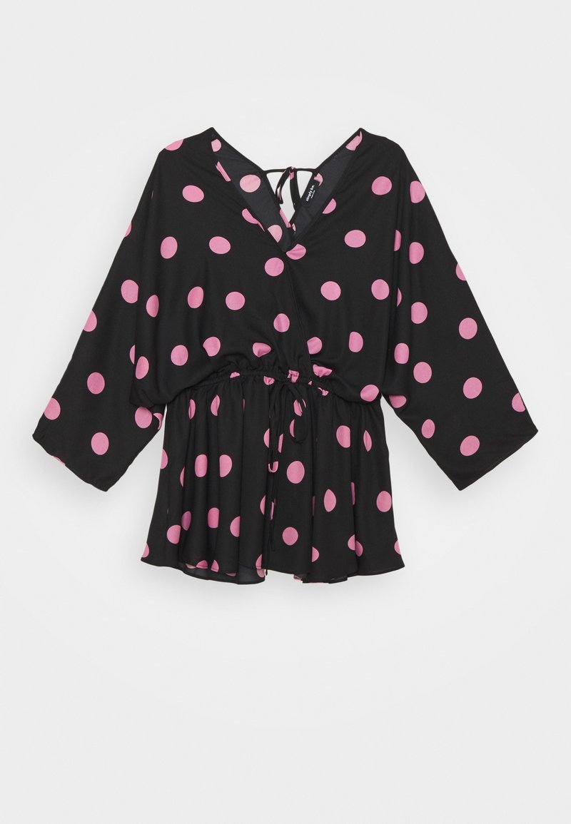 Blouse noire à manches longues, avec des pois roses, un lien au dos au niveau du col, et une taille à cordon élastique.